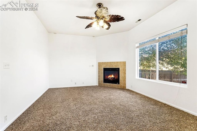 unfurnished living room with carpet, a tile fireplace, and ceiling fan