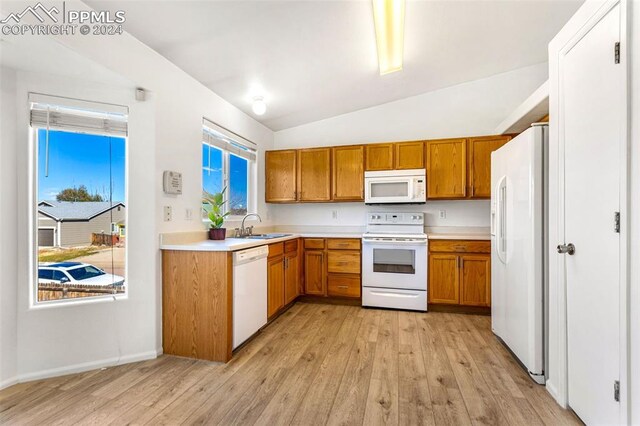 kitchen with light wood-type flooring, white appliances, sink, and vaulted ceiling