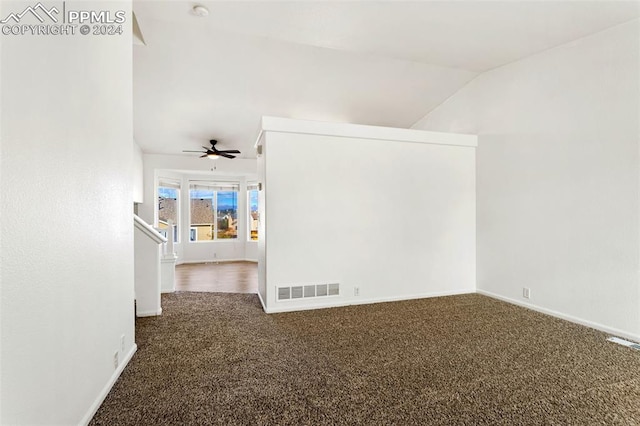 empty room featuring dark carpet, vaulted ceiling, and ceiling fan