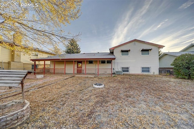 back of property with central air condition unit and a fire pit