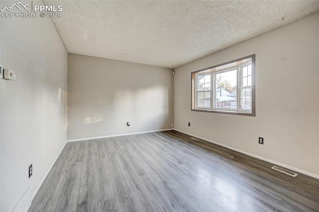 unfurnished room featuring a textured ceiling and hardwood / wood-style flooring