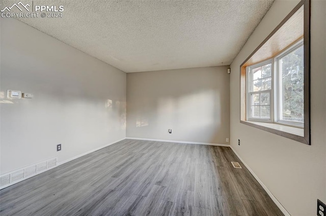 spare room with a textured ceiling and hardwood / wood-style flooring