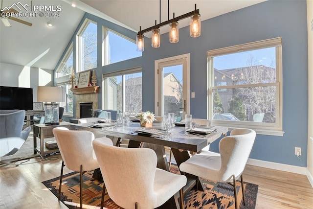 dining room with ceiling fan, light wood-type flooring, and high vaulted ceiling