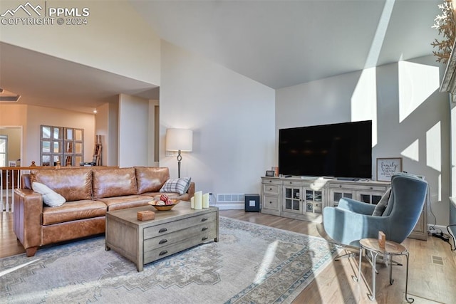 living room featuring a high ceiling and light hardwood / wood-style flooring