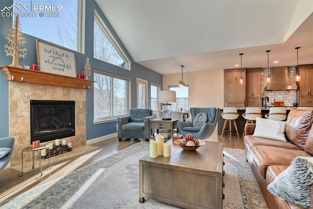 living room with lofted ceiling, light wood-type flooring, and a tile fireplace