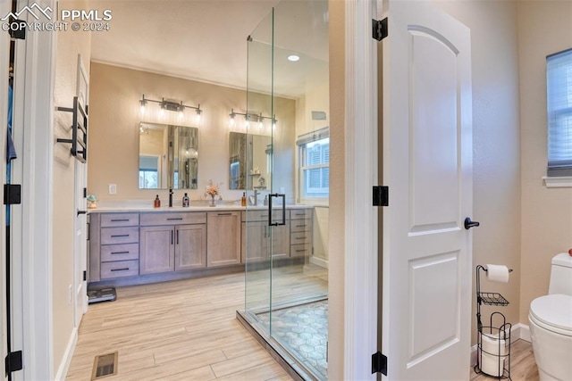 bathroom featuring wood-type flooring, vanity, toilet, and a shower with shower door