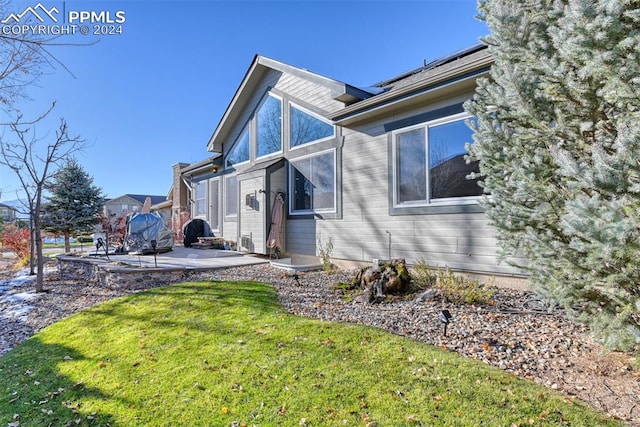 view of side of home featuring a lawn and a patio area