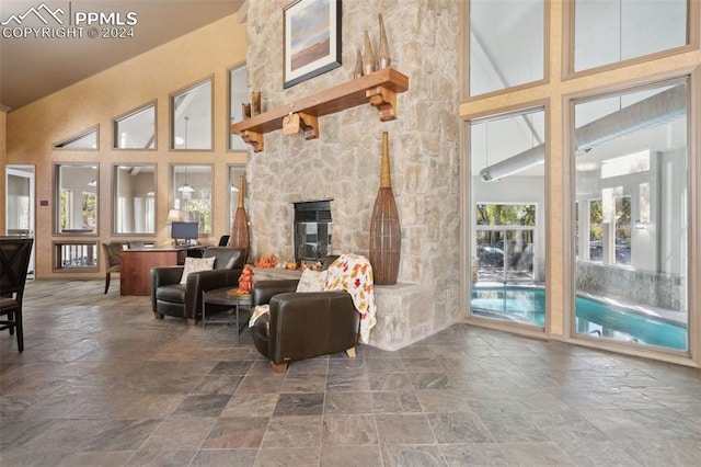 living room with a stone fireplace and high vaulted ceiling