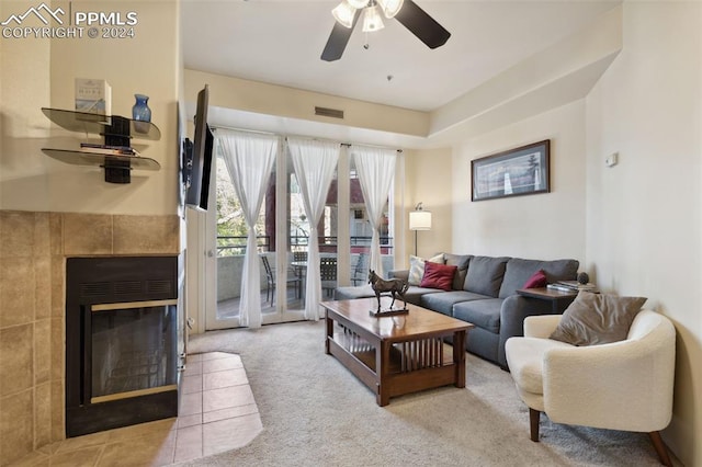 carpeted living room featuring ceiling fan and a tile fireplace