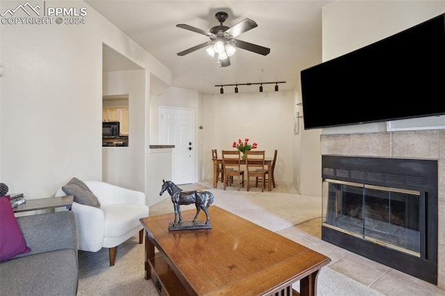 carpeted living room featuring a fireplace and ceiling fan