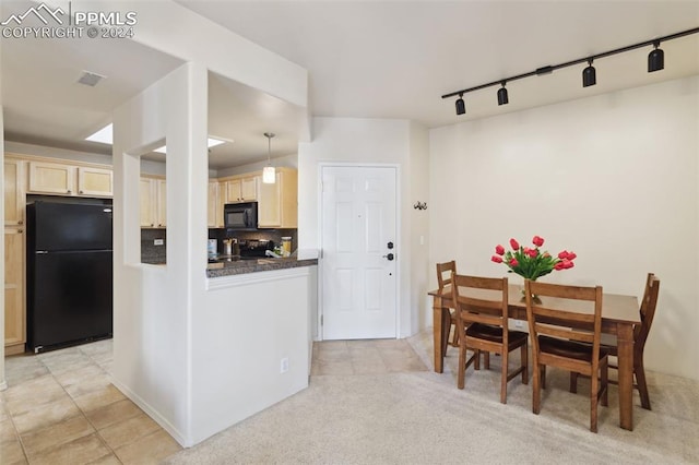 kitchen featuring track lighting, decorative backsplash, hanging light fixtures, black appliances, and light carpet