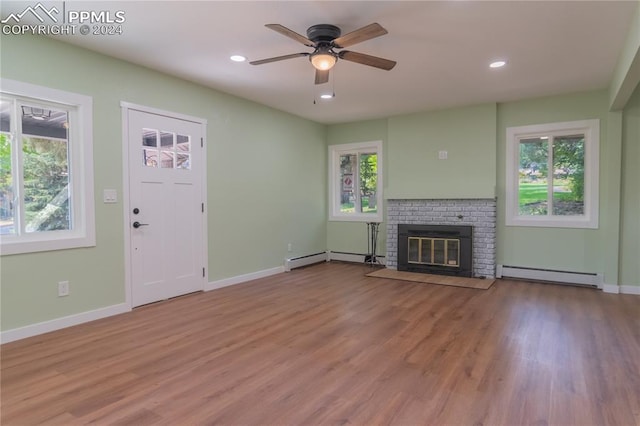 unfurnished living room with a wealth of natural light, baseboard heating, and light hardwood / wood-style floors