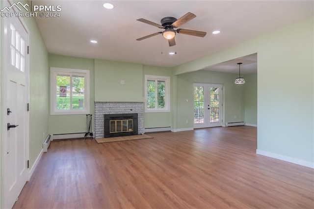 unfurnished living room featuring a brick fireplace, wood-type flooring, ceiling fan, and a baseboard heating unit