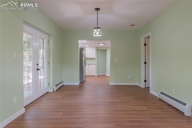 unfurnished dining area featuring light hardwood / wood-style floors, a baseboard radiator, and french doors