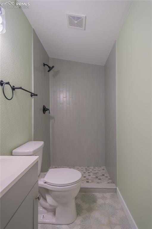 bathroom with toilet, vanity, and a tile shower