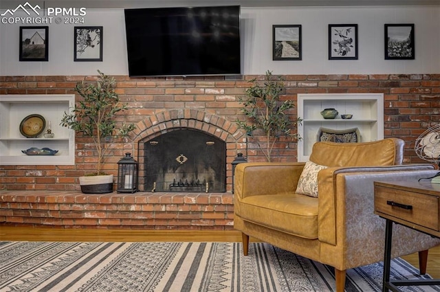 living area with a fireplace, built in features, and hardwood / wood-style flooring