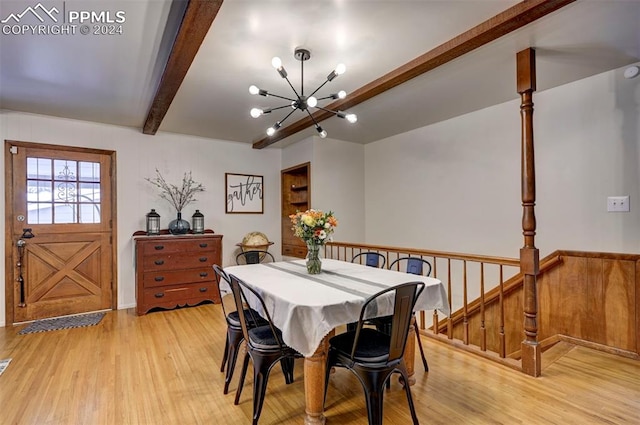 dining space with light hardwood / wood-style floors, beam ceiling, and an inviting chandelier