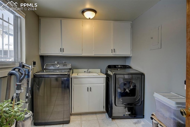 laundry area featuring cabinets, sink, light tile patterned floors, electric panel, and washer and dryer