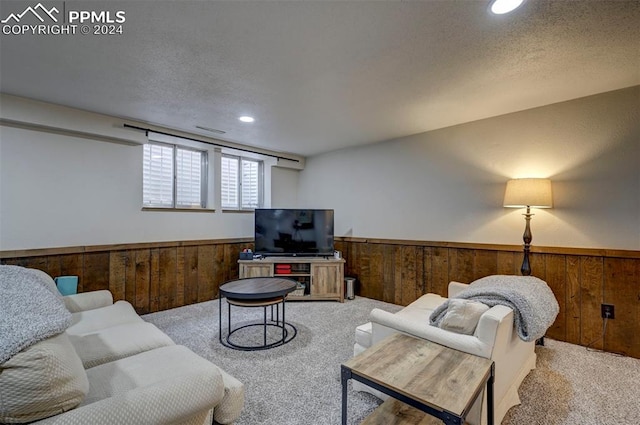 carpeted living room featuring wooden walls and a textured ceiling