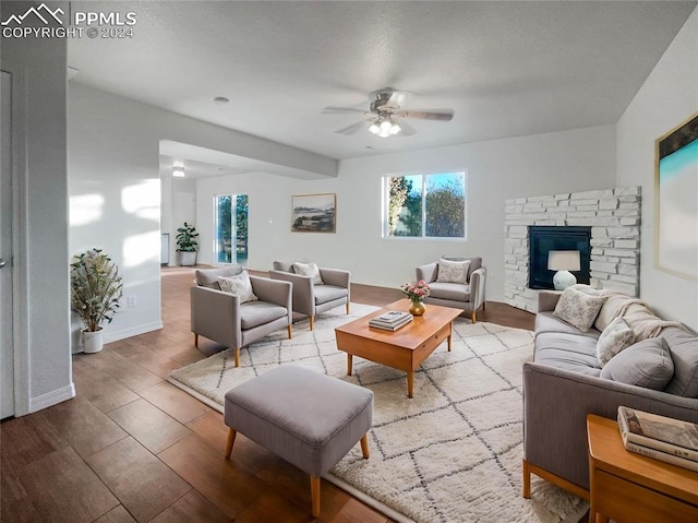 living room featuring a fireplace, wood-type flooring, and ceiling fan