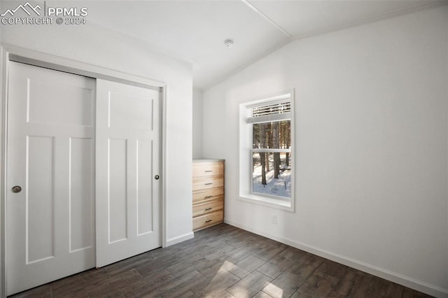 unfurnished bedroom with vaulted ceiling, a closet, and dark wood-type flooring