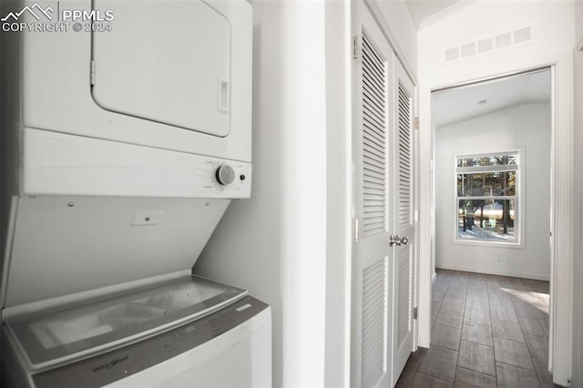 laundry room with dark hardwood / wood-style floors and stacked washing maching and dryer