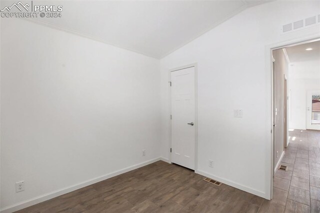 unfurnished room with dark hardwood / wood-style flooring and lofted ceiling