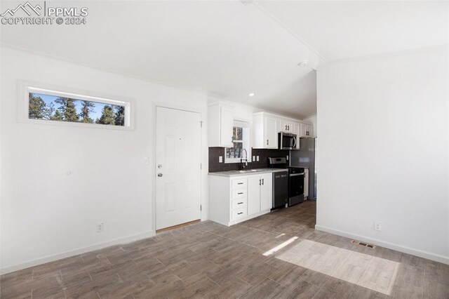 kitchen featuring decorative backsplash, appliances with stainless steel finishes, sink, light hardwood / wood-style flooring, and white cabinetry