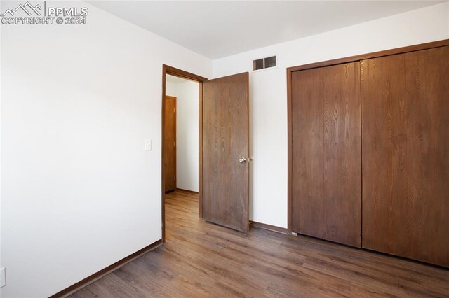 unfurnished bedroom featuring a closet and dark wood-type flooring