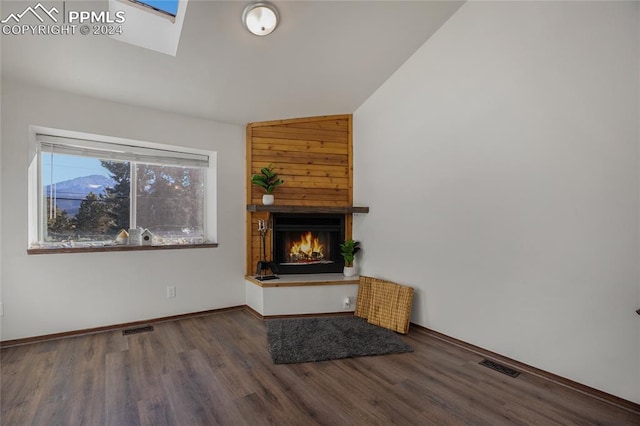 unfurnished living room featuring vaulted ceiling with skylight, a large fireplace, and wood-type flooring