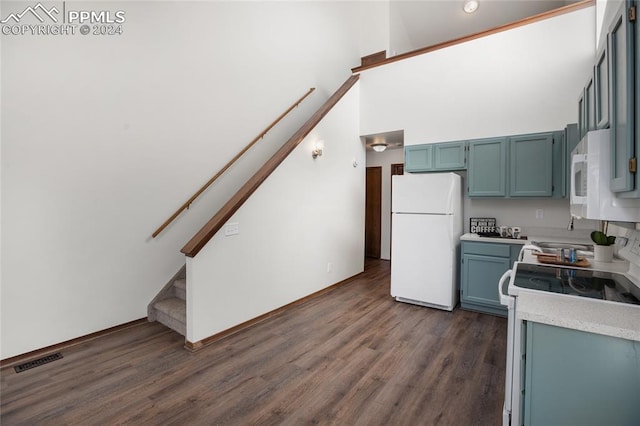 kitchen featuring blue cabinetry, white appliances, dark wood-type flooring, and high vaulted ceiling