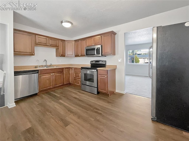 kitchen with appliances with stainless steel finishes, sink, and dark hardwood / wood-style flooring