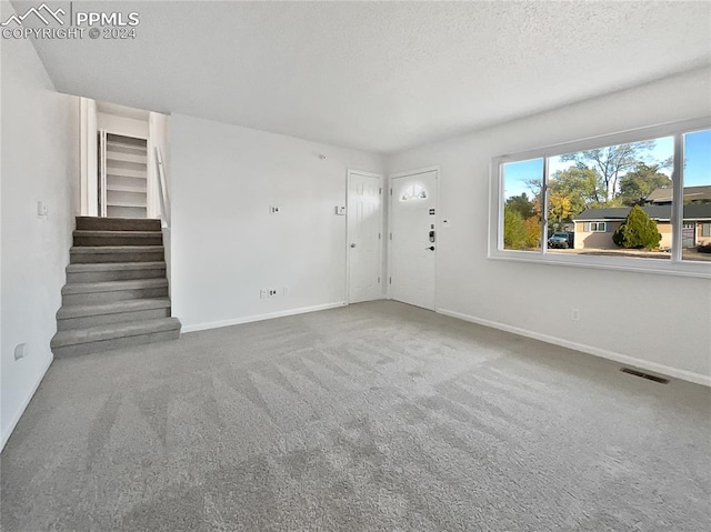 unfurnished living room with carpet and a textured ceiling