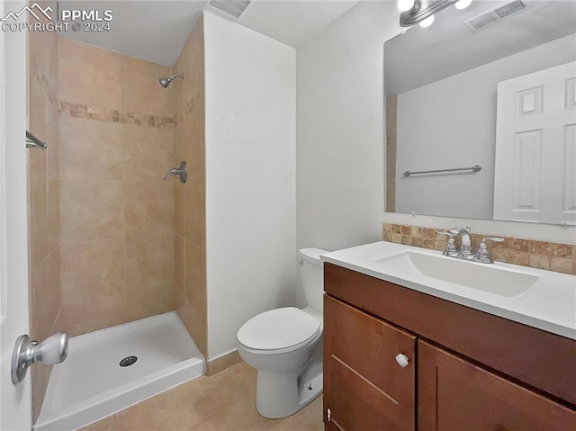 bathroom with tile patterned floors, vanity, toilet, and tiled shower