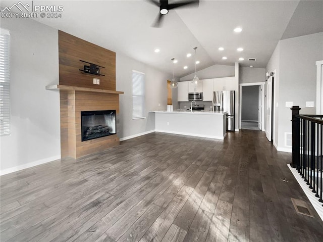 unfurnished living room with vaulted ceiling, sink, dark hardwood / wood-style floors, ceiling fan, and a fireplace