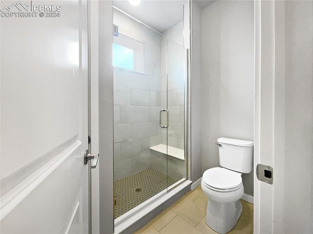 bathroom with toilet, tile patterned floors, and a shower with door