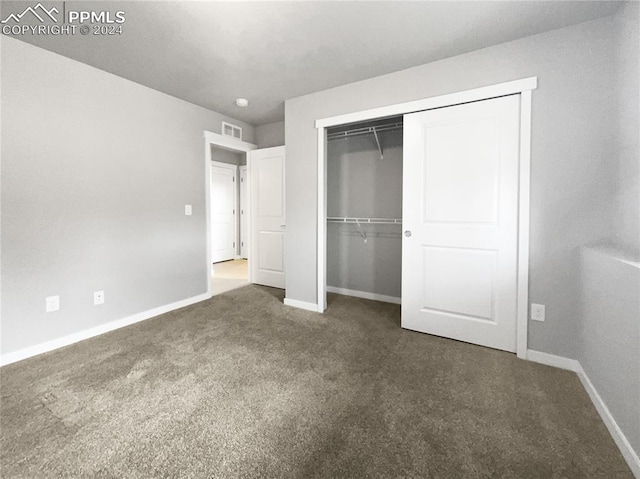 unfurnished bedroom with a closet and dark carpet