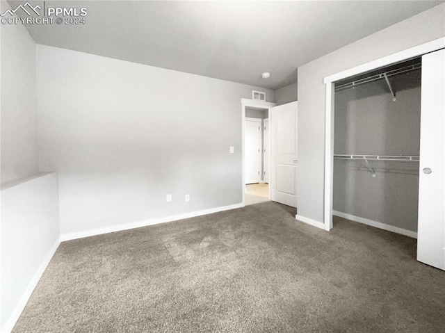 unfurnished bedroom with a closet and dark colored carpet