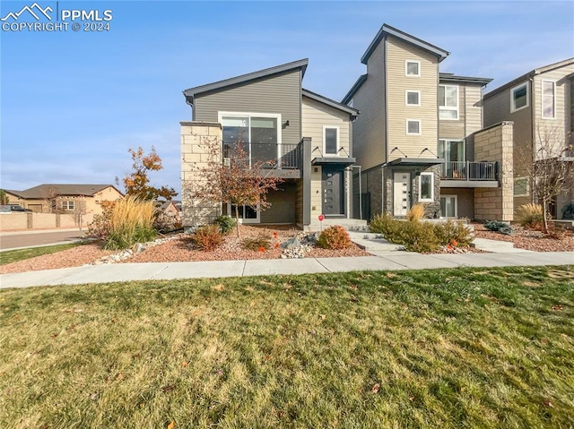 view of front of house featuring a front yard and a balcony