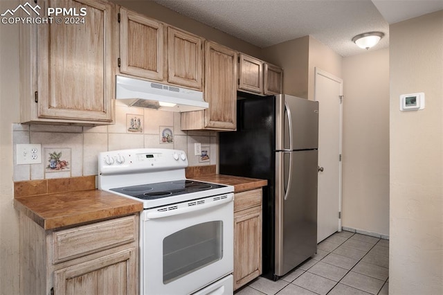 kitchen with light brown cabinetry, stainless steel refrigerator, decorative backsplash, and white range with electric cooktop