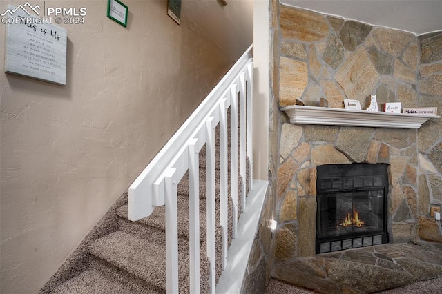 staircase with carpet flooring and a fireplace