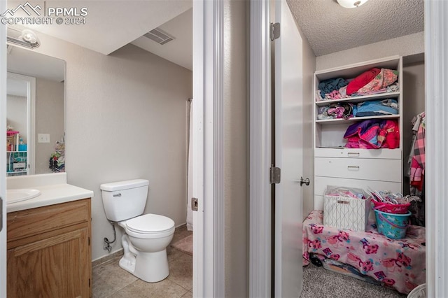 bathroom with tile patterned floors, vanity, toilet, and a textured ceiling