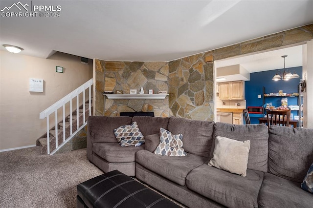 living room with a stone fireplace, carpet floors, and a notable chandelier