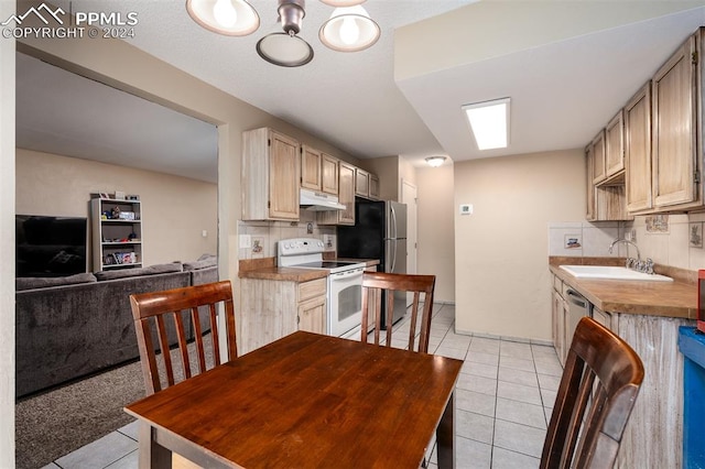 kitchen with stainless steel appliances, sink, decorative backsplash, and light brown cabinets