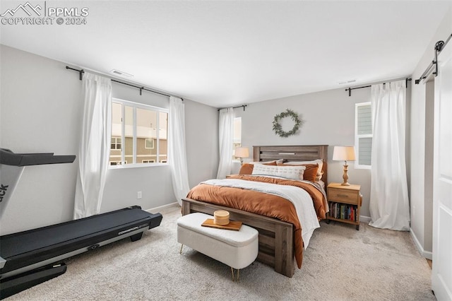 bedroom featuring a barn door and light carpet