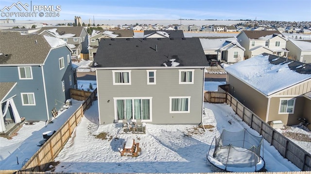 snow covered rear of property with a trampoline