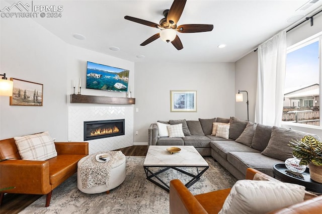 living room with hardwood / wood-style flooring, ceiling fan, and a tile fireplace