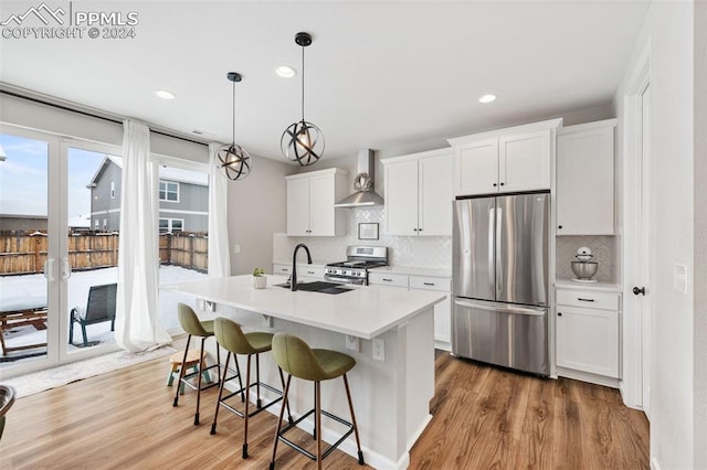 kitchen with white cabinetry, wood-type flooring, wall chimney exhaust hood, and stainless steel appliances