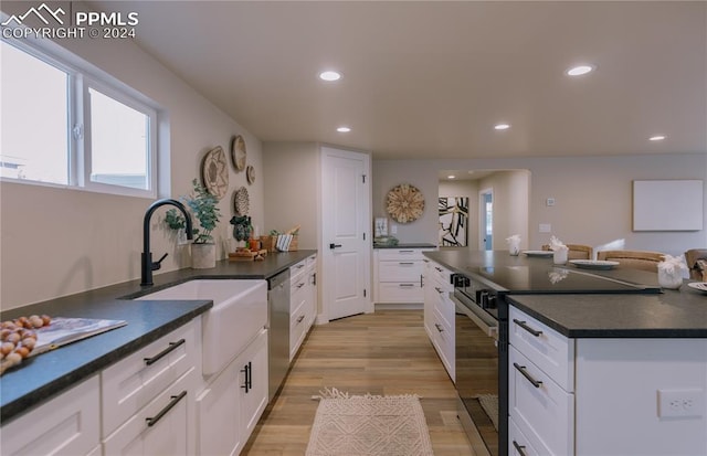 kitchen with white cabinets, sink, appliances with stainless steel finishes, and light hardwood / wood-style flooring