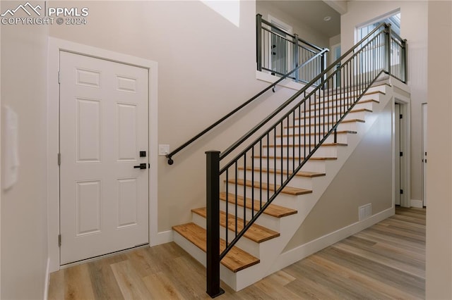 stairway with hardwood / wood-style floors and a towering ceiling